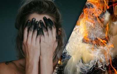 verzweifelte rußbefleckte Frau und qualmender Scheiterhaufen