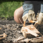 Bild zweier behandschuhter Hände, die ein Feuer entzünden