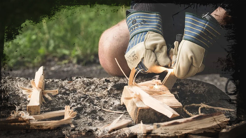 Bild zweier behandschuhter Hände, die ein Feuer entzünden